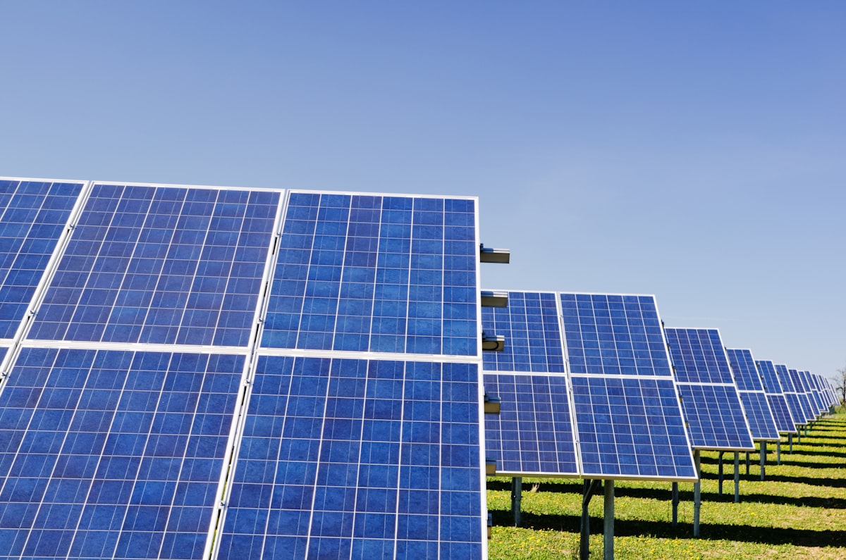 Solar panels on flat green farmland under clear sky
